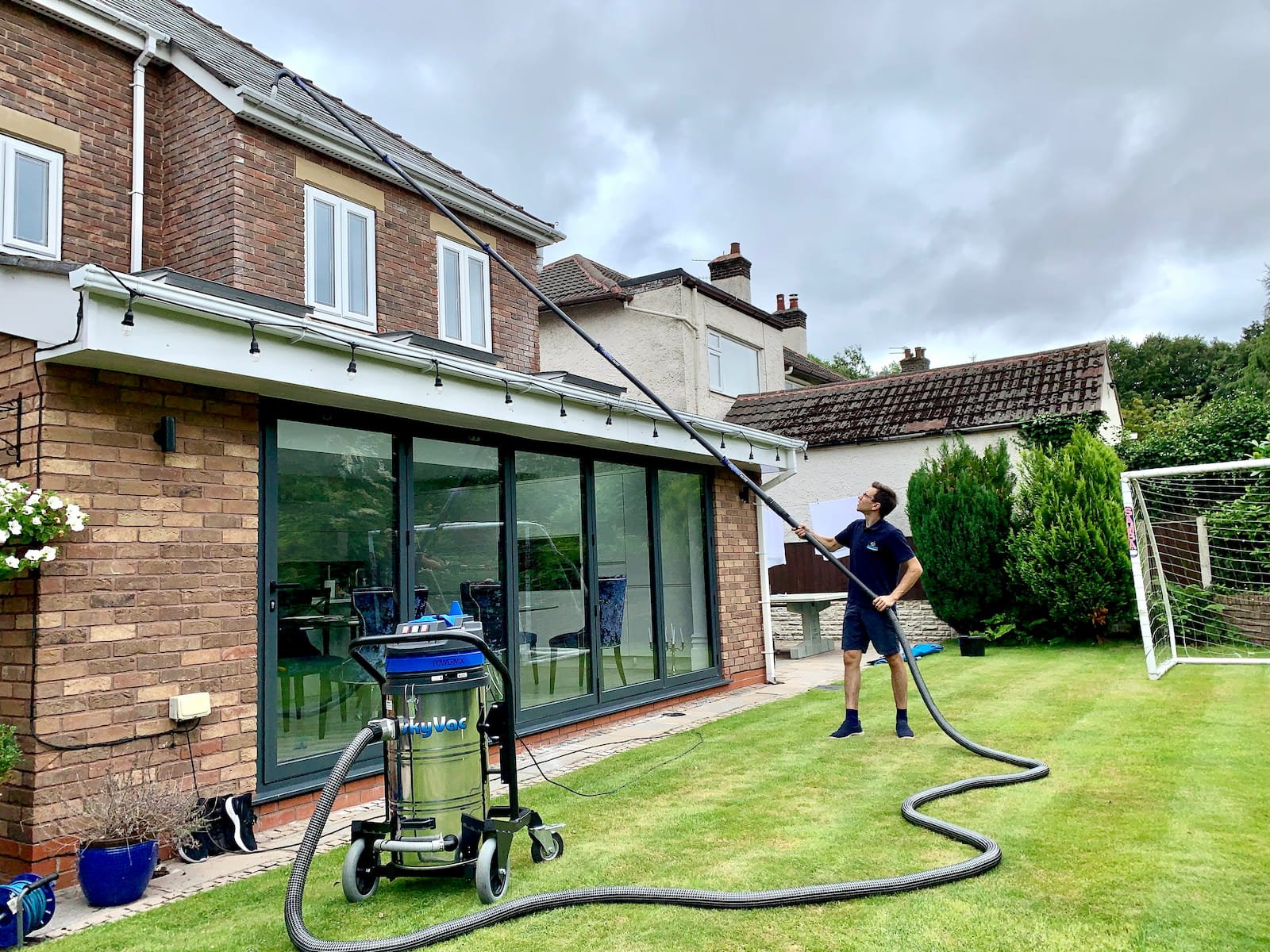 Gutter cleaning over an extension using a high-reach gutter vacuum